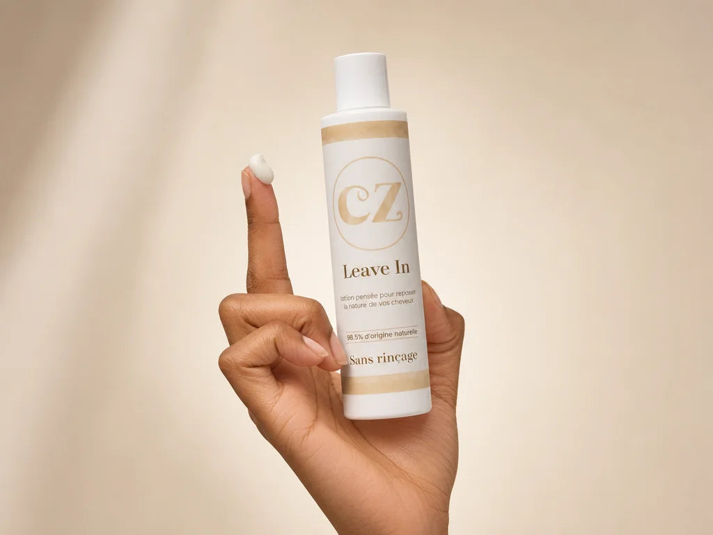 Clean product photography, 4:3. A woman's hand holding the Curlizz Leave-In flacon upright, with a s
